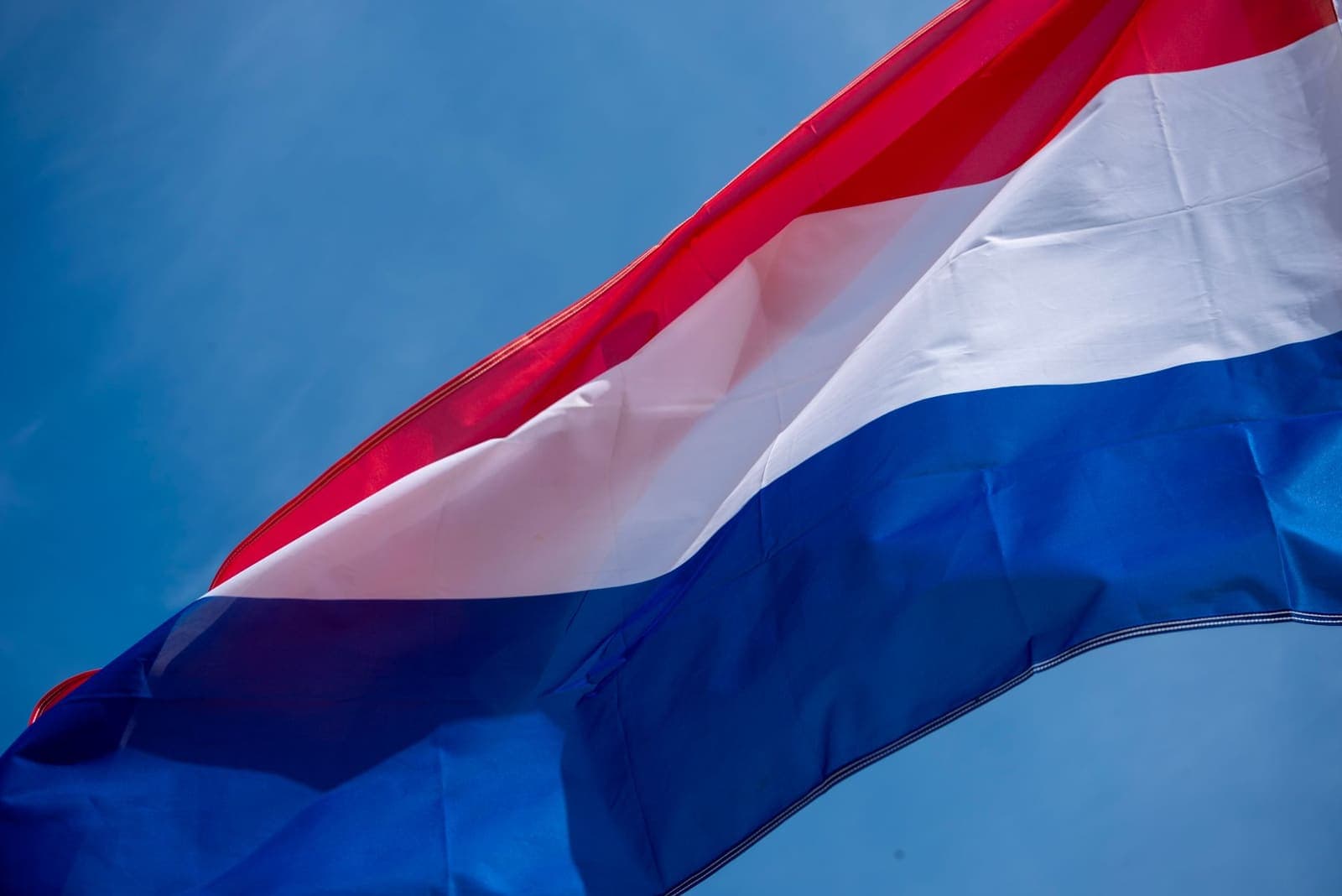 Dutch flag waving against a blue sky